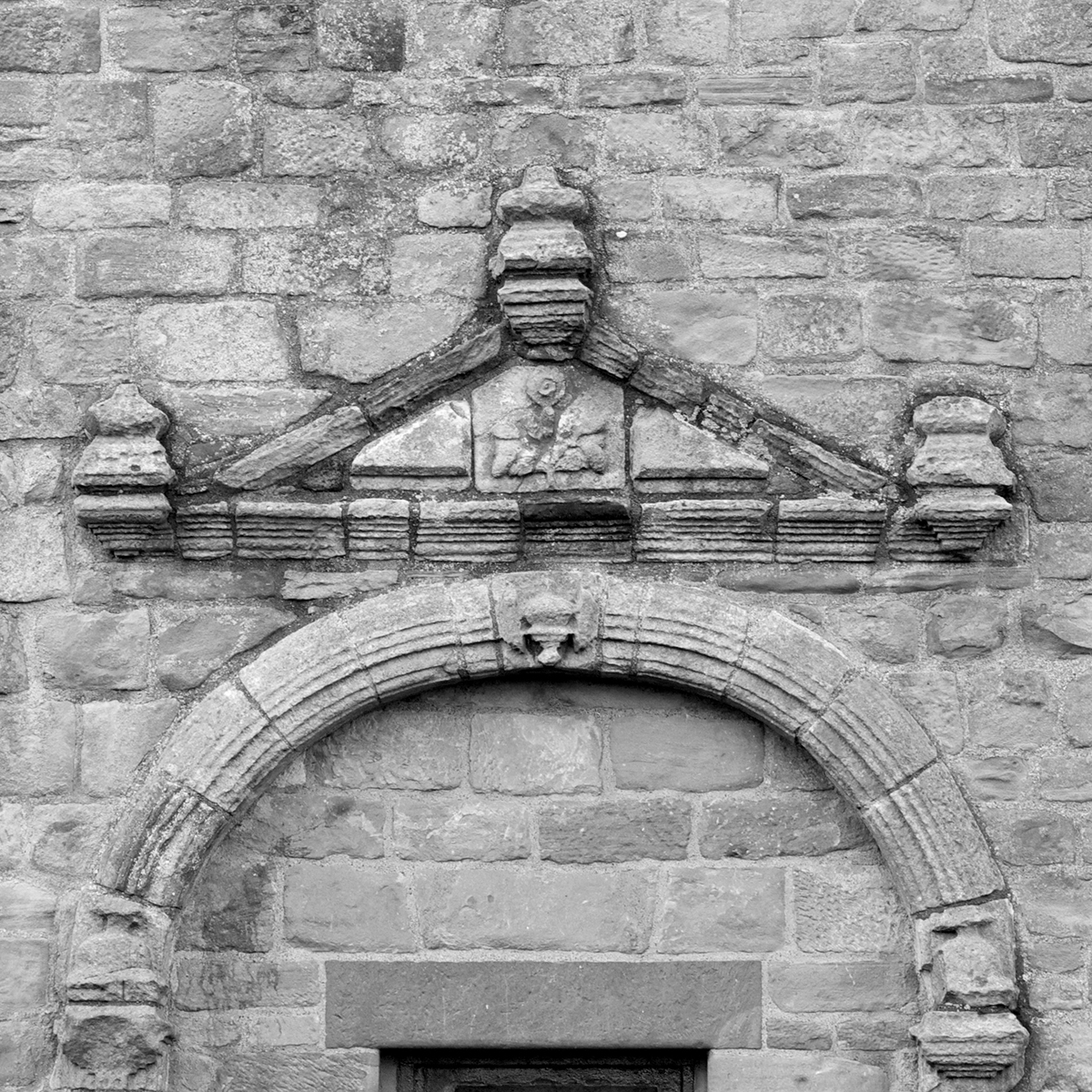 Close up greyscale photo of decorated entrance doorway pediment